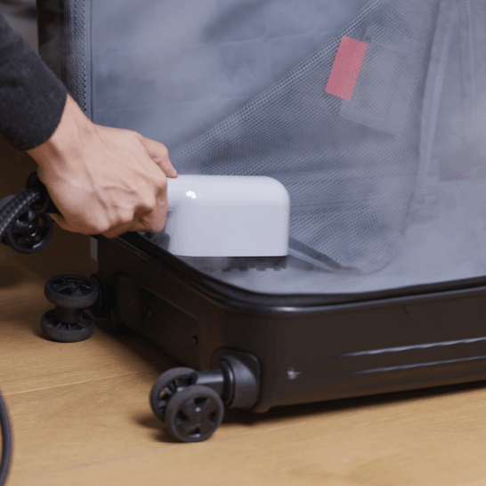 Black luggage being steamed with Laurastar IZZI on the floor by a male